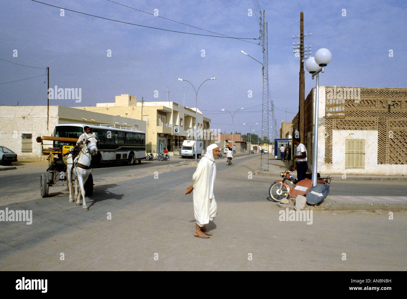 Straßenszene in Gabes ein Pferd zeigt gezogenen Wagen, ein Mann zu Fuß und einen modernen Reisebus im Hintergrund. Stockfoto