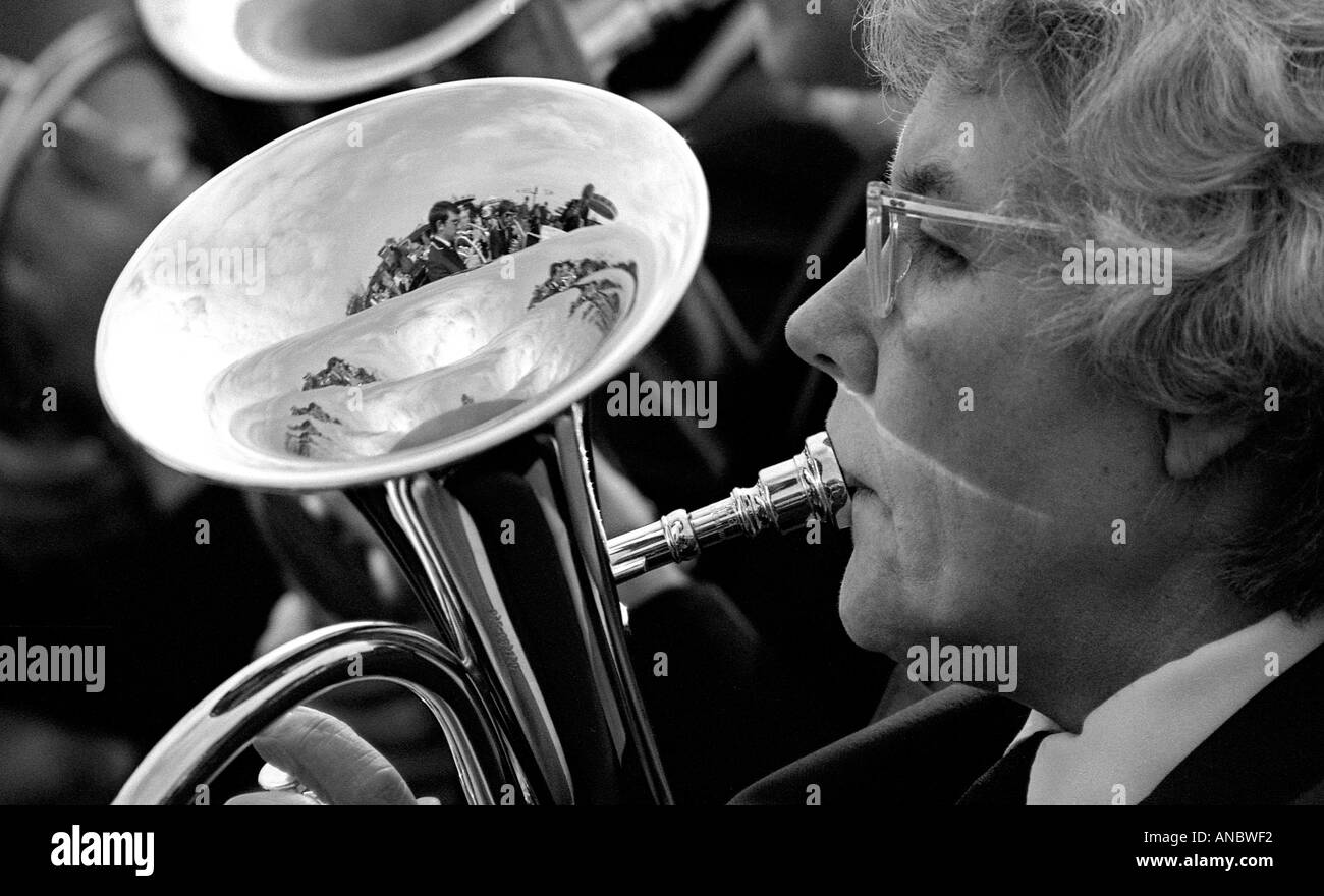 Nahaufnahme von Dame spielt Trompete in einer Blaskapelle mit Reflexion der anderen Bandmitglieder in das helle Metall Stockfoto