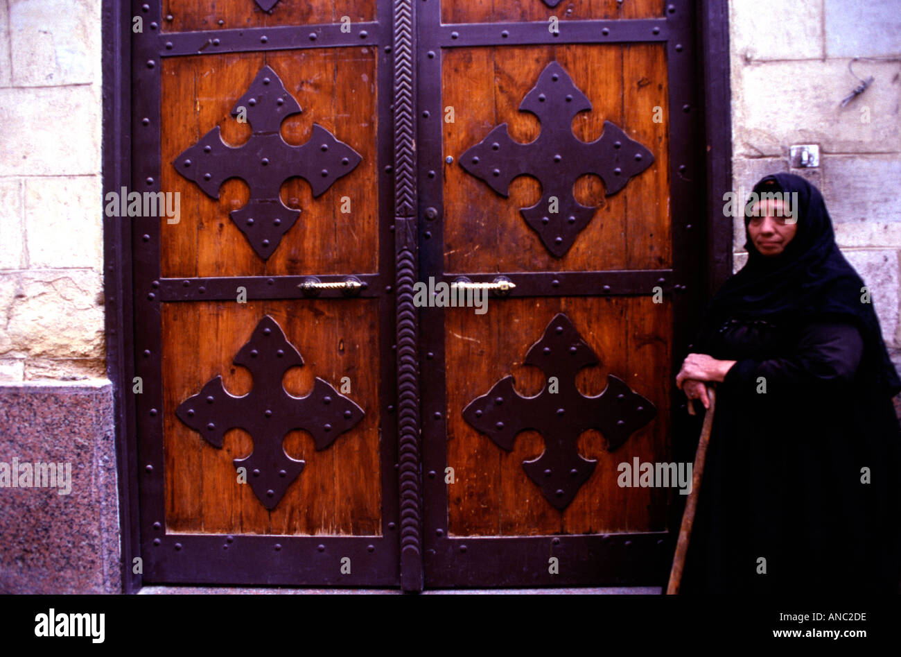 Ältere ägyptische christliche Frau am Eingang der Griechisch-orthodoxen Kirche von St. George, dekoriert mit Kreuzen in der Koptischen viertel Kairo Ägypten Stockfoto