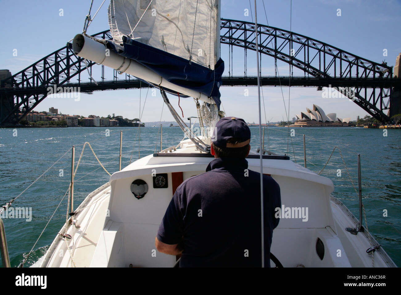 Yacht mit Steuermann unter Segeln nahenden SydneyHarbour Brücke. Stockfoto