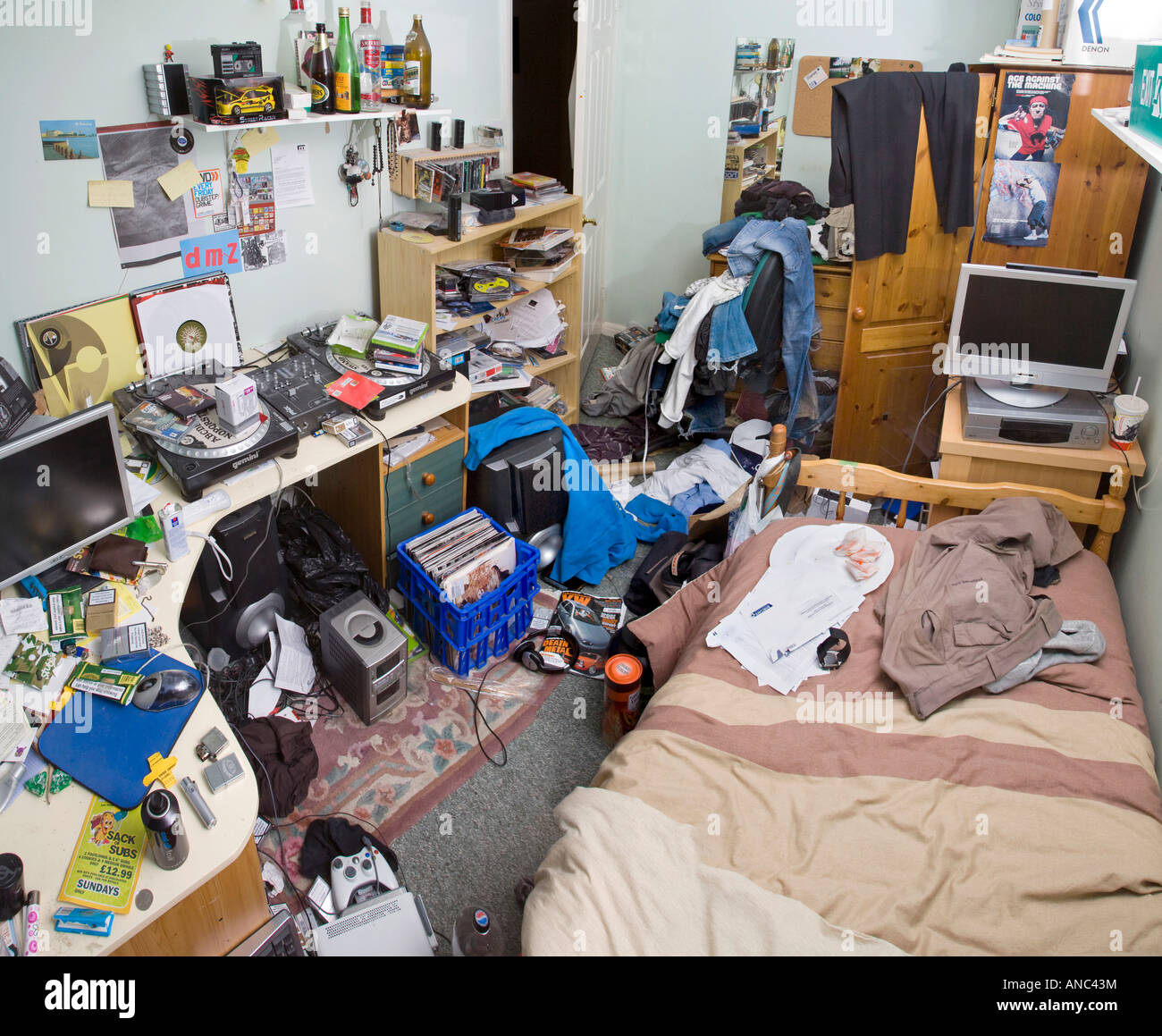 EINE MÄNNLICHE TEENAGER-SCHLAFZIMMER IN EIN DURCHEINANDER MIT KLEIDUNG UND MÜLL ÜBERALL LIEGEN Stockfoto