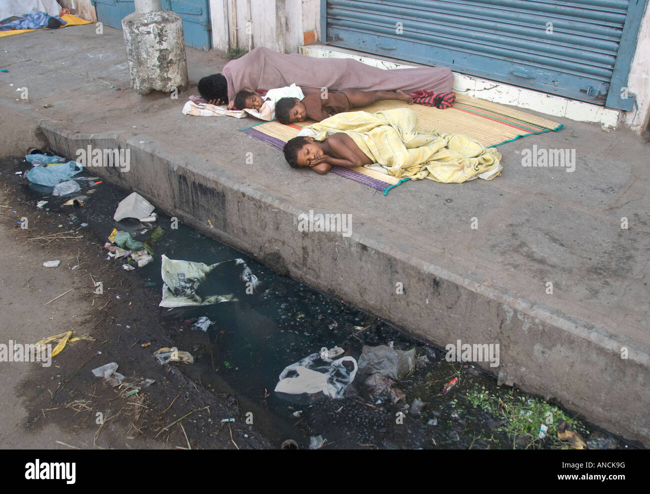 Eine Obdachlose Mutter und ihre Kinder schlafen auf einem Bürgersteig in Indien Stockfoto