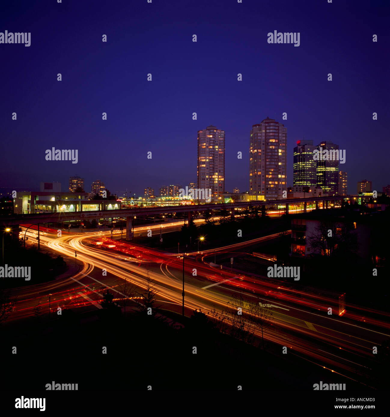 Burnaby, BC, Britisch-Kolumbien, Kanada - hohe Aufstieg Gebäude am Metrotown, Straße Ampel Streifen in der Nacht Stockfoto
