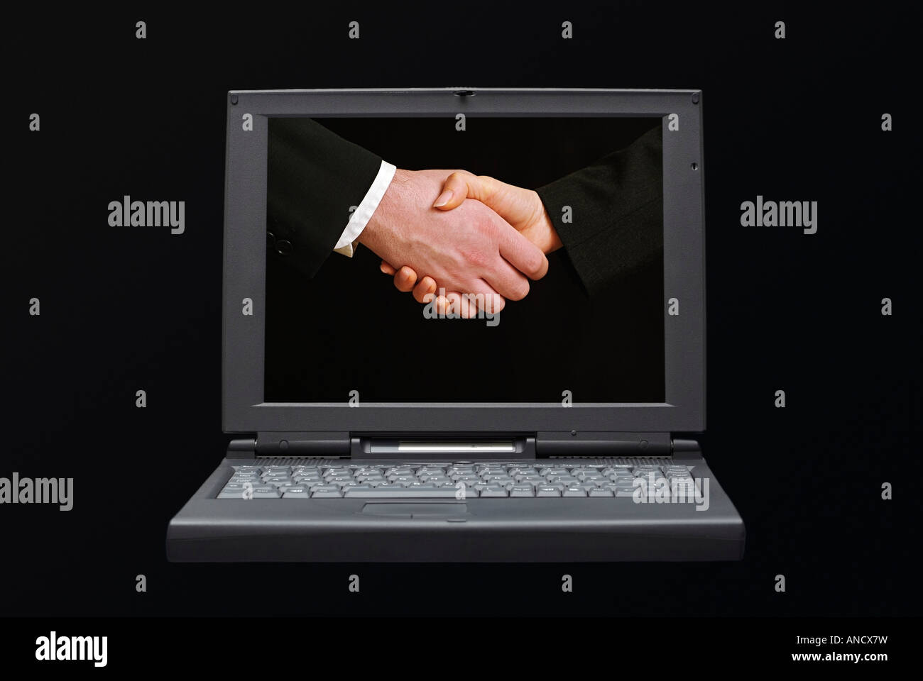 Laptop-Computer mit Geschäftsleute Händeschütteln auf dem Bildschirm vor einem schwarzen Hintergrund angezeigt Stockfoto