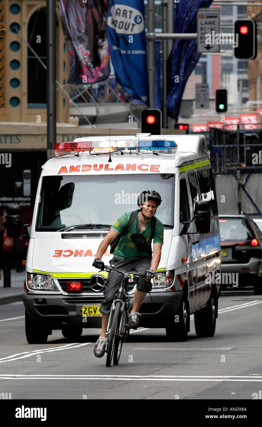Ein Fahrradkurier eilt der rasende Krankenwagen aus dem Weg zu Stockfoto