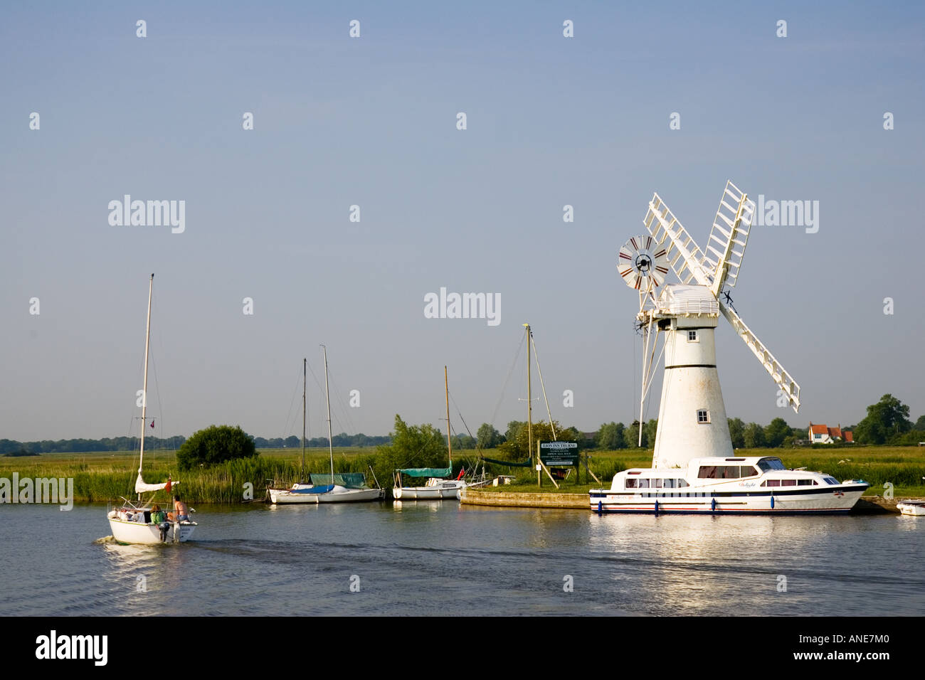 Segelboote und Fluss-Kreuzfahrtschiffe passieren Windmühle auf Norfolk Broads Vereinigtes Königreich Stockfoto