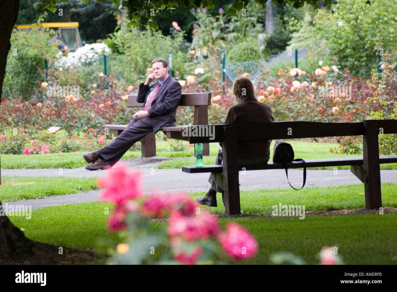 Mann und Frau einander gegenüber sitzen und sprechen nicht auf Parkbänken. Tralee, Irland. Stockfoto