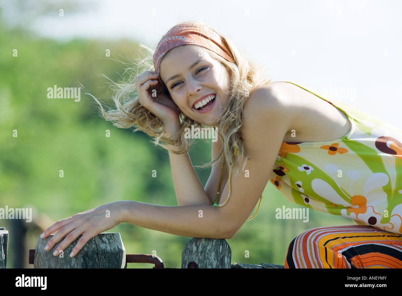 Junge Frau sitzt oben auf Holzzaun, lachen Stockfoto