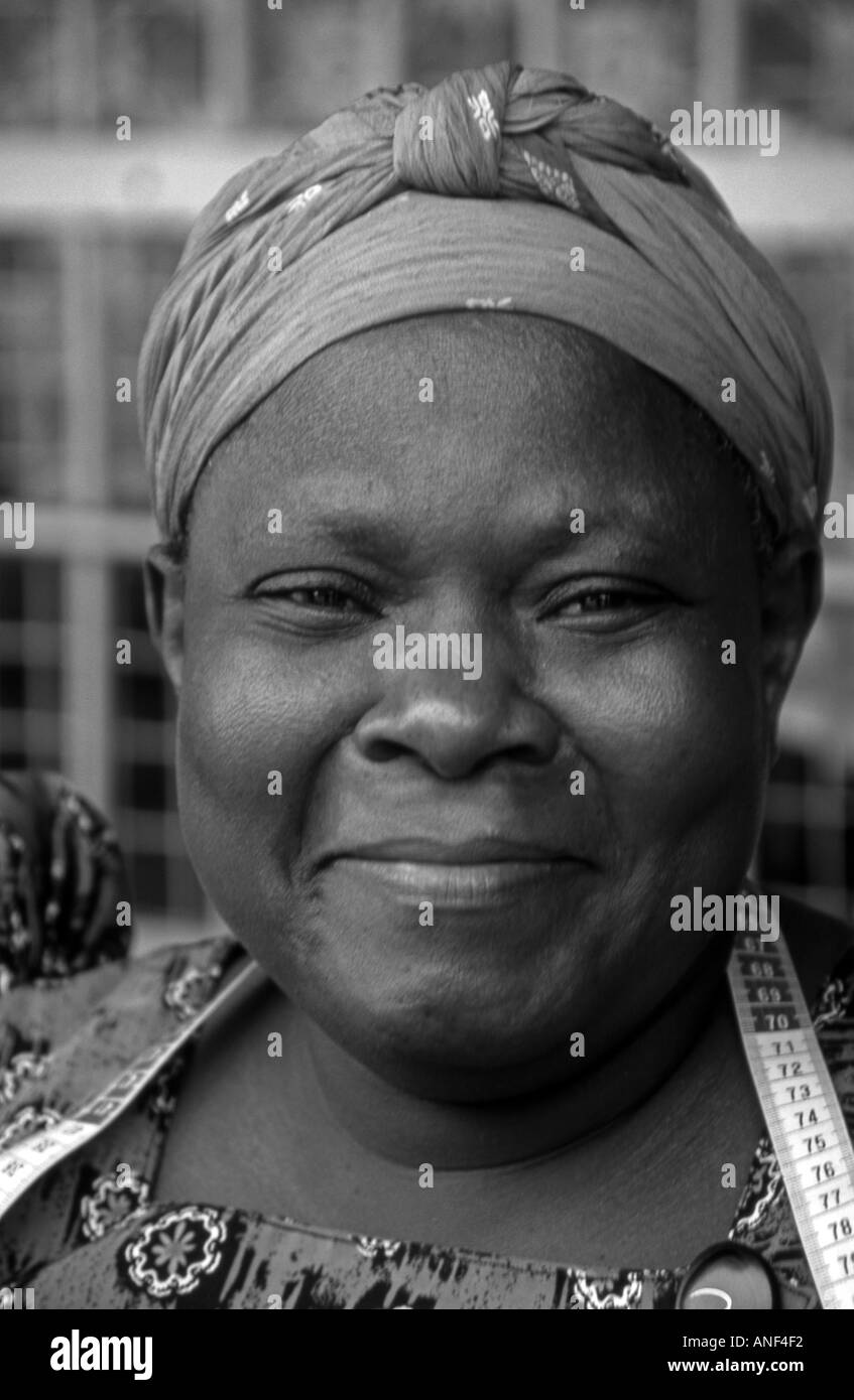 Lächelnd Mitte im Alter von afrikanischen Straße Schneider Frau in bunten Trachten & Hut Jinja-City-Uganda-Ost-Afrika Stockfoto