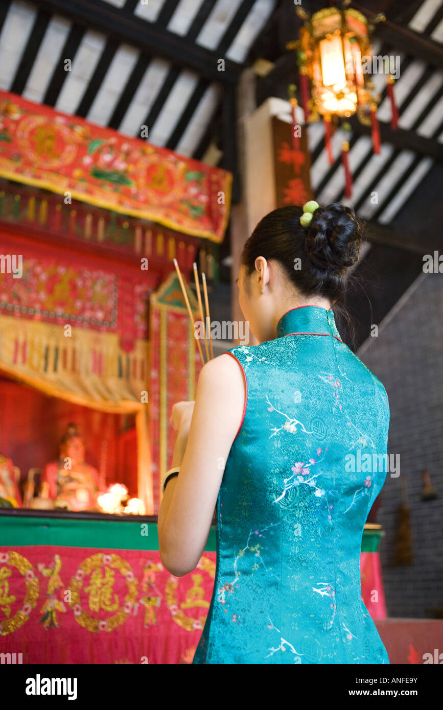 Junge Frau trägt traditionellen chinesischen Kleidung hält Weihrauch im Tempel Stockfoto
