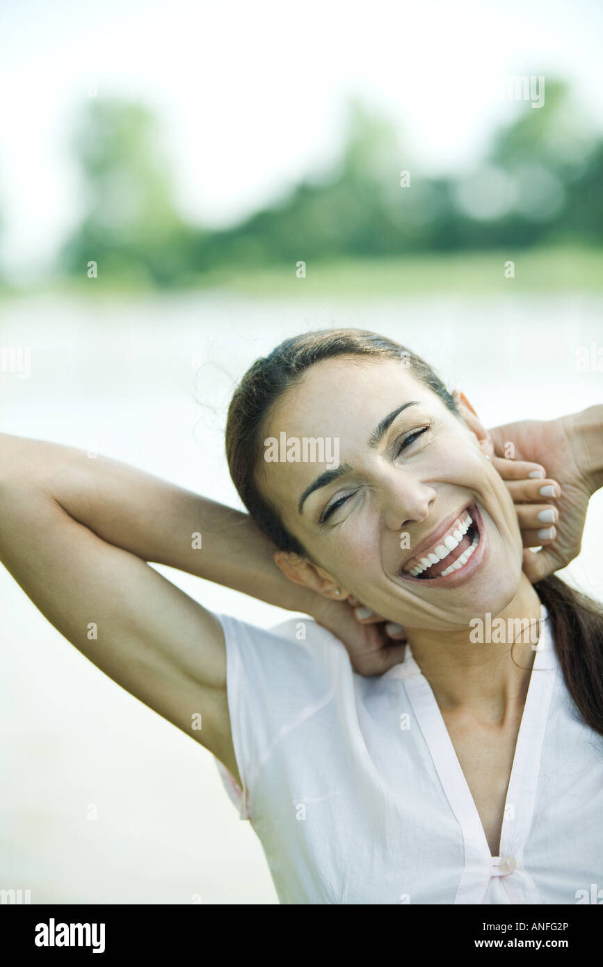 Frau im Freien, die Hände hinter dem Kopf, lachen, Kopf und Schultern Stockfoto