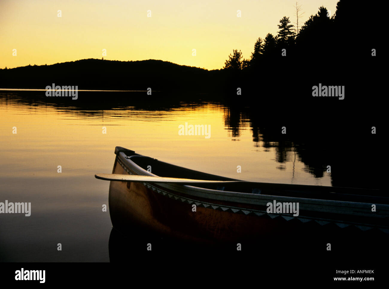 Die Sillhouette eines Kanus als es liegt am Ufer eines Sees bei Sonnenuntergang auf See stand im Alqonguin Provincial Park, Ontario, kann Stockfoto