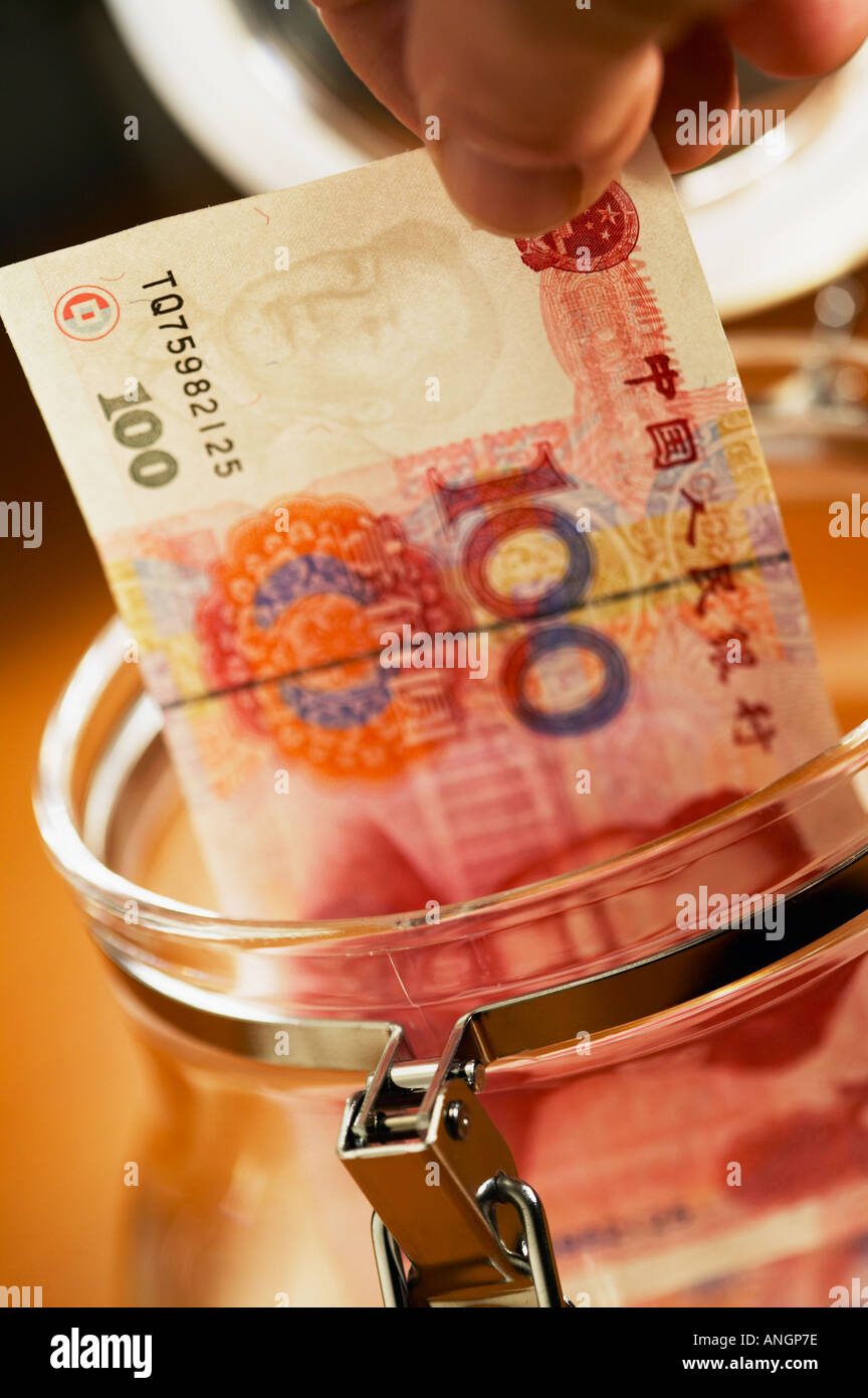 Nahaufnahme von Fingern mit chinesischen hundert Yuan-Banknote und Glas Vorratsgefäß Stockfoto