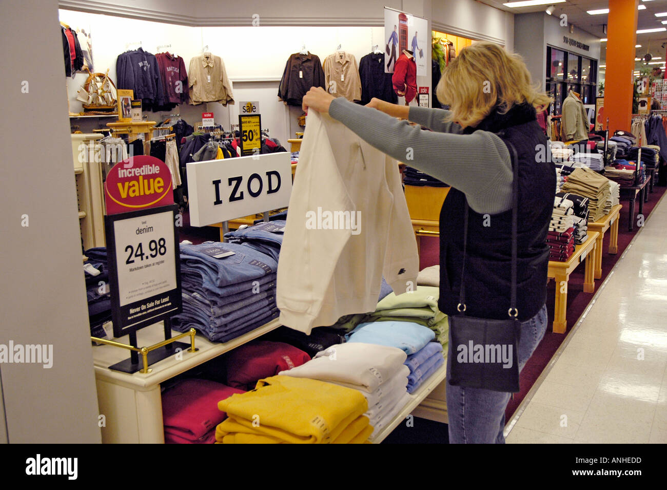 Frau schaut Kleidung und Preise vor dem Kauf in einem Geschäft in einem Einkaufszentrum Stockfoto