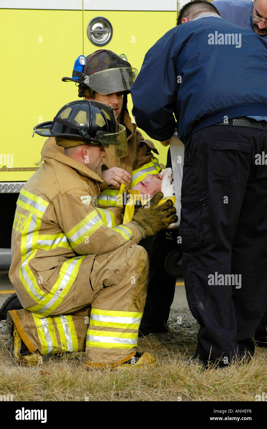 Feuerwehrleute kümmern sich um verletzte Crash-Opfer eines Kopfes auf Automobil Absturz Auto Auto Stockfoto