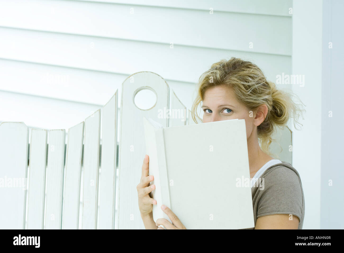 Frau über Buch in die Kamera schauen Stockfoto