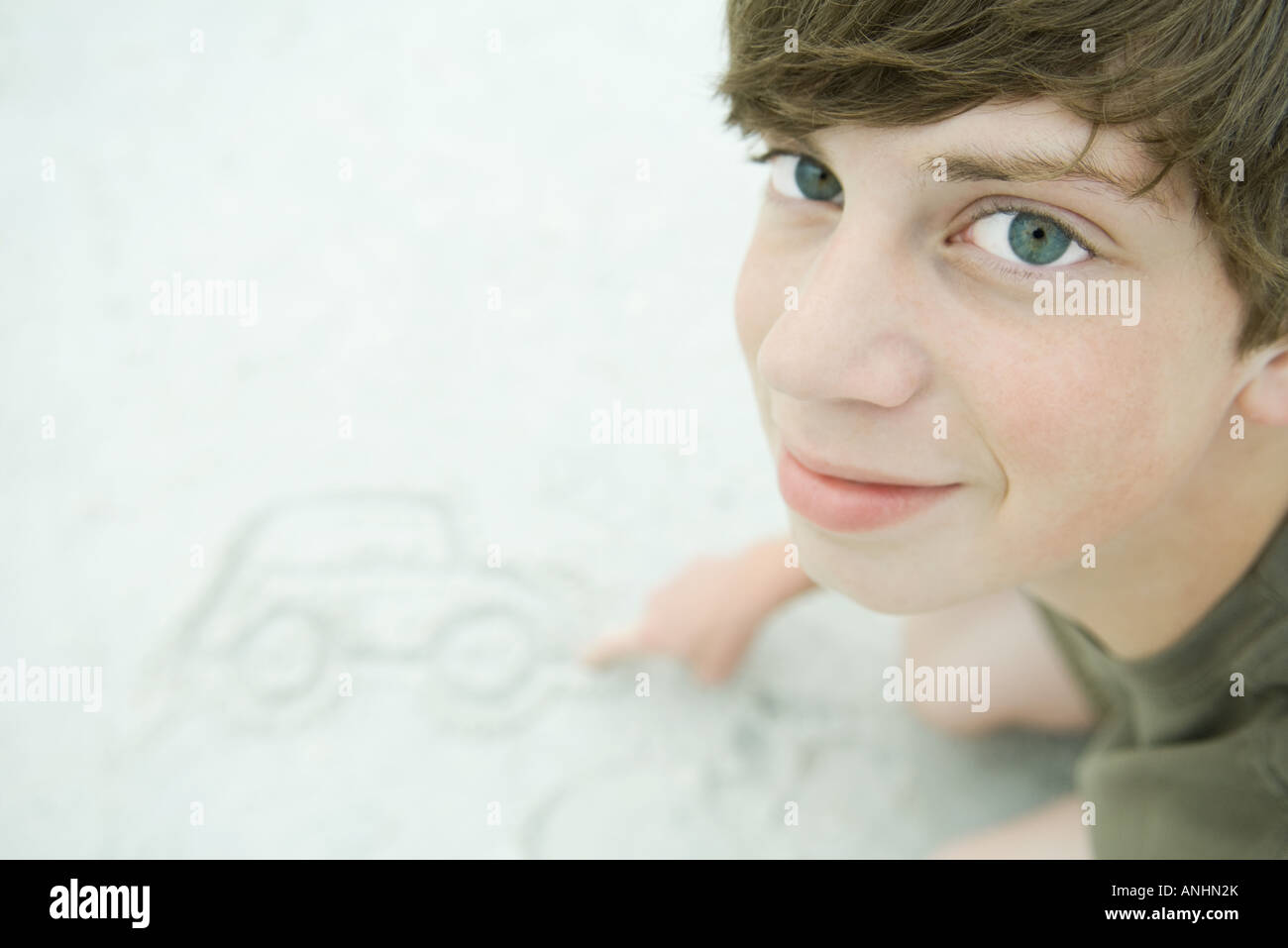 Teenboy zeichnen Auto in Sand, blickte zu Kamera Stockfoto