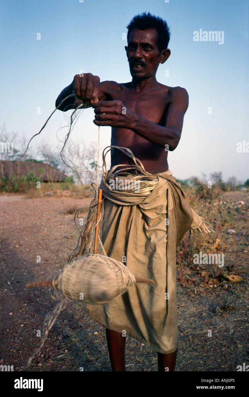 Ein Dorfbewohner im ländlichen Gujarat, der eine uralte Technik des Verdrehens/Spinnens der Sisalanlage verwendet, um Seil oder Schnur zum Weben zu machen. Indien Stockfoto