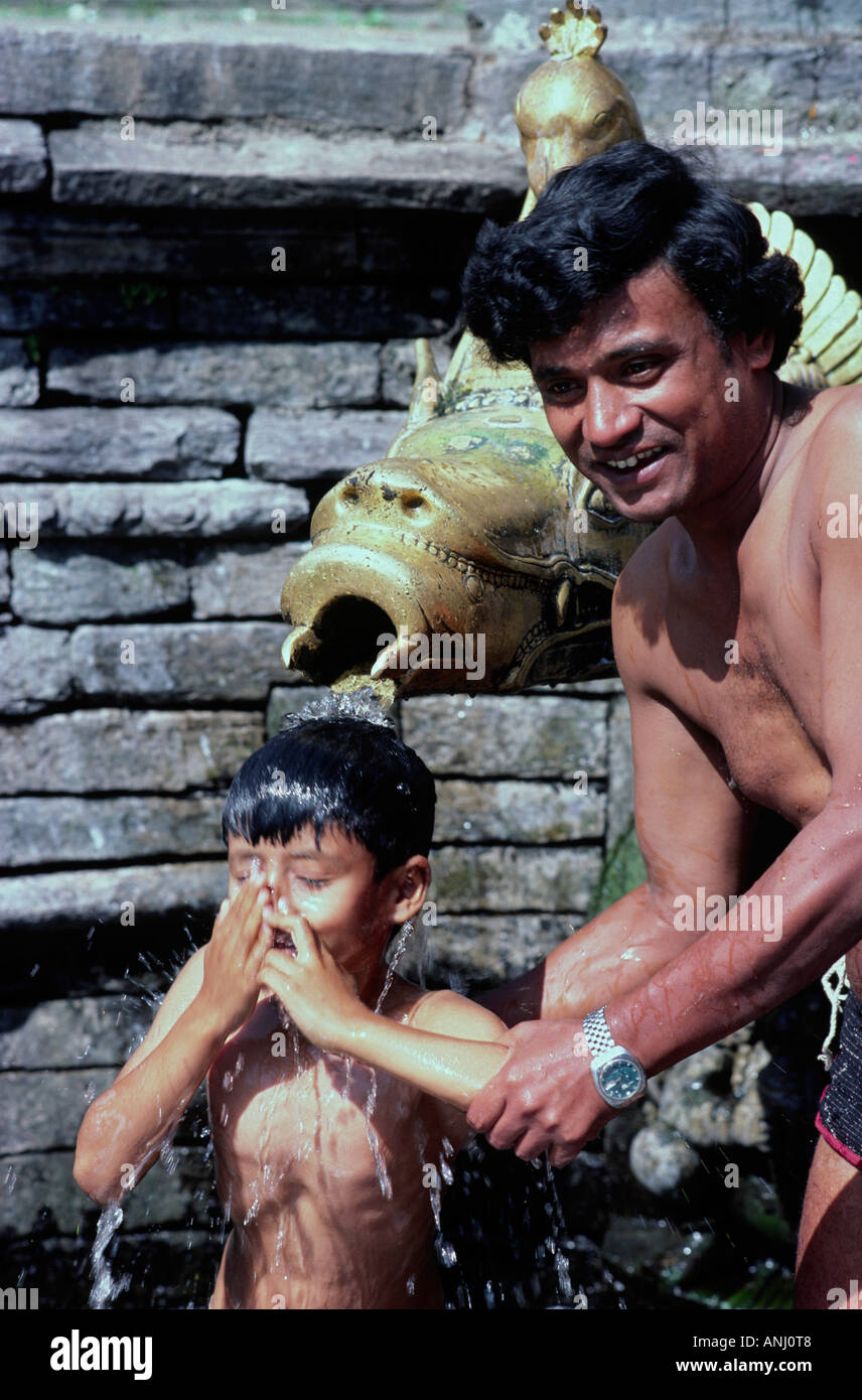 Vater badet seinen Sohn an einem heiligen Ort in Kathmandu in Wasser. Nepal Stockfoto