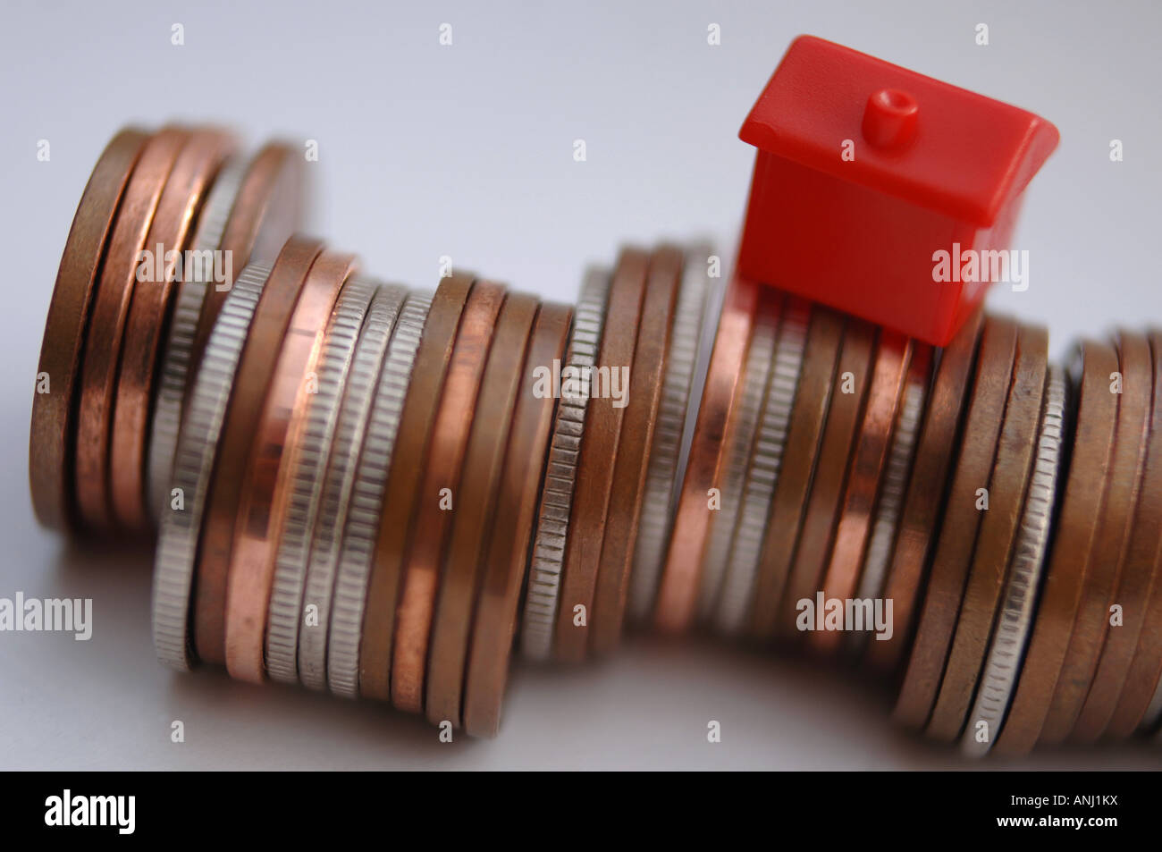Eine rote Monolopy Haus stehen auf einem Haufen Münzen, Immobilienpreise, Darlehen und Hypotheken zu illustrieren Stockfoto