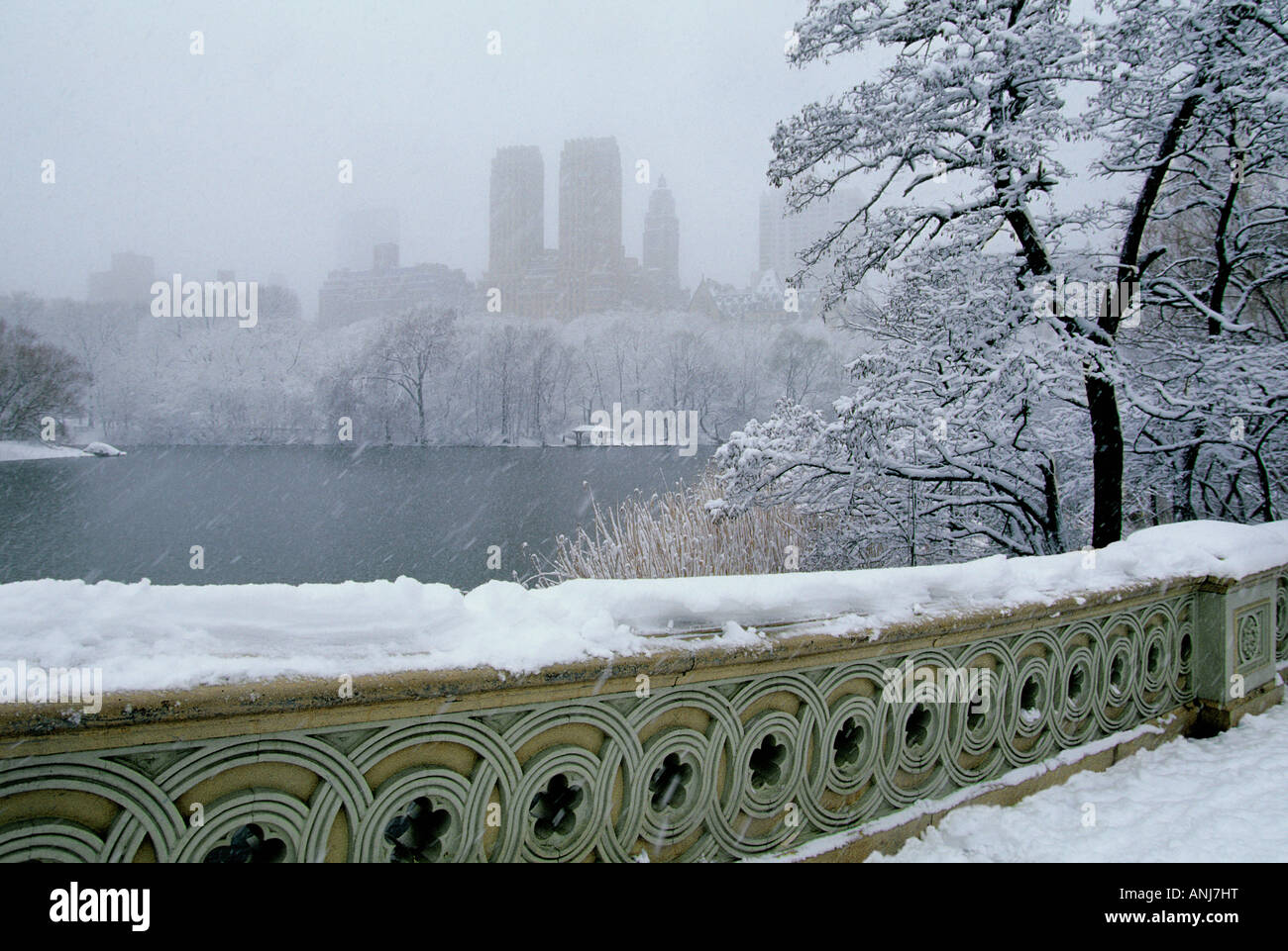 Bogenbrücke im Central Park New York. Schnee. Winterwetter Schneesturm. Manhattan Skyline des Central Park West in der Ferne. Schneebedeckte Bäume. USA Stockfoto