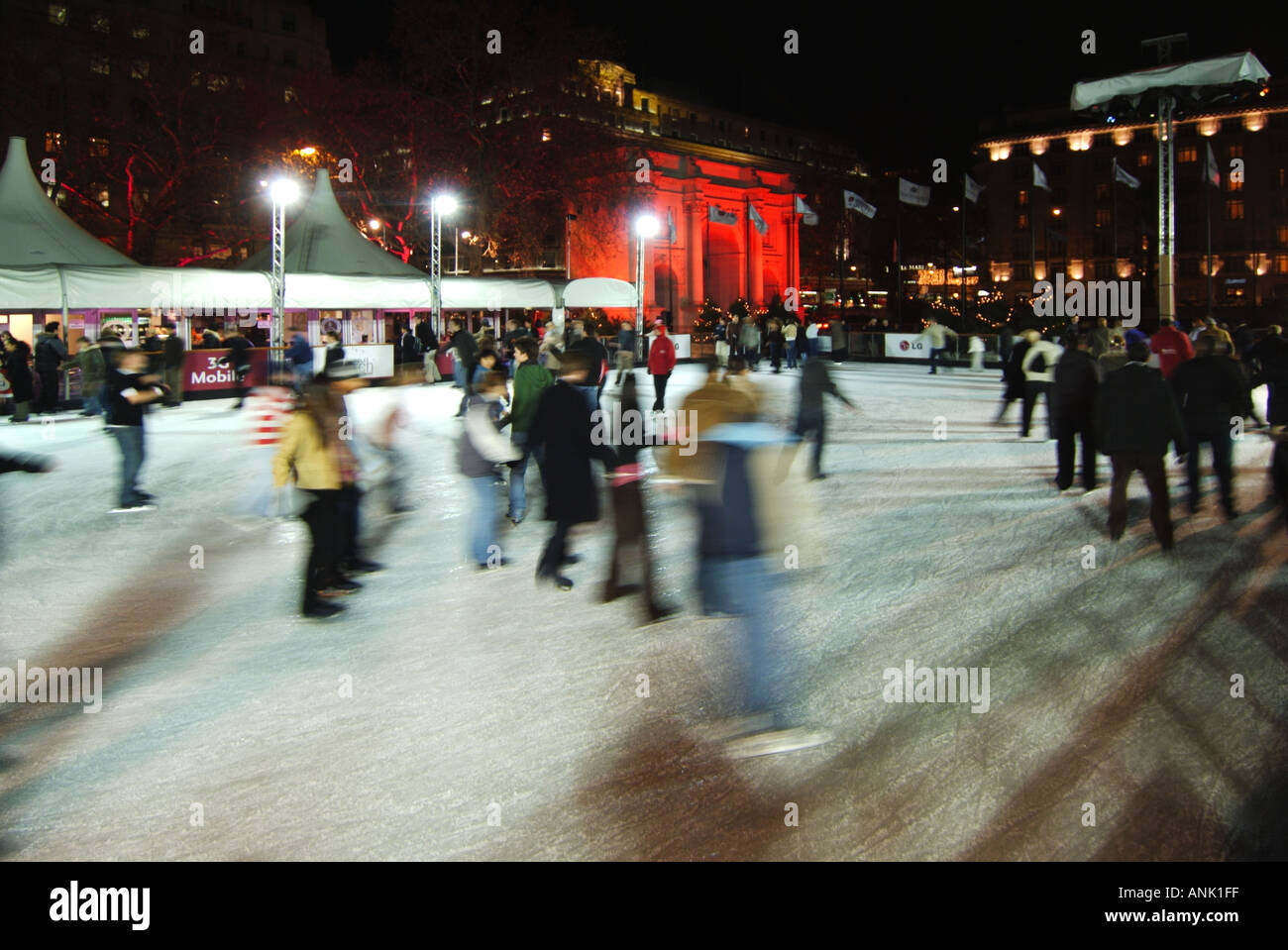 Bewegungsunschärfen Skater Menschen auf Eisbahn bei Flutlicht Weihnachten Wintersaison Skating Event West End Marble Arch rot beleuchtet Flutlichter London England Großbritannien Stockfoto