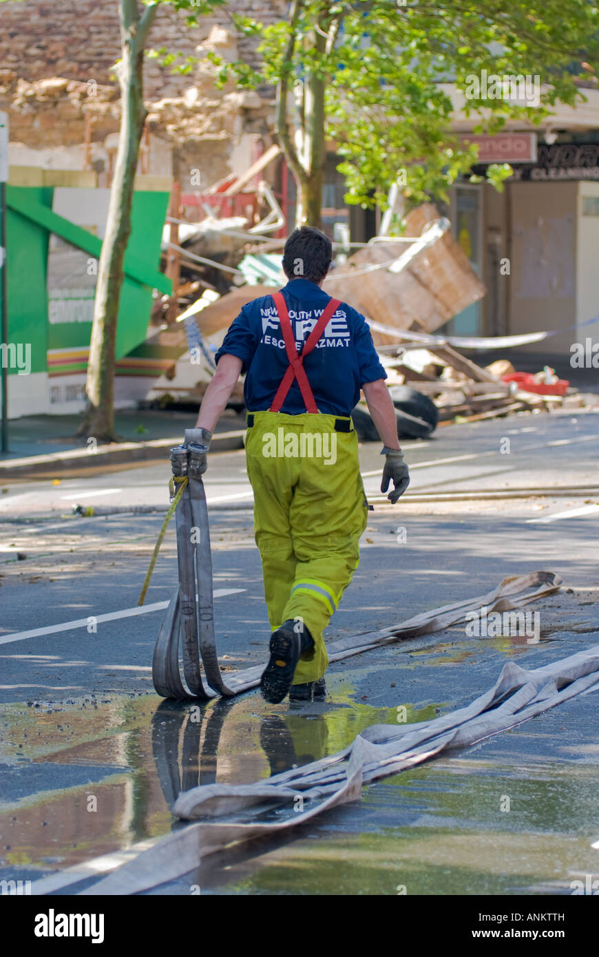 Fire Fighter am Arbeitsplatz Aufräumen nach dem Abriss eines Gebäudes Stockfoto