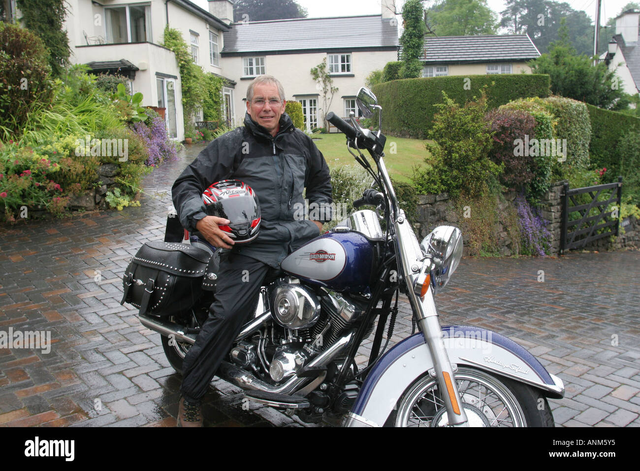 60 Jahre alten Mann mit Harley-Davidson Motorrad außerhalb seines Hauses Leute Lifestyle Wales Stockfoto