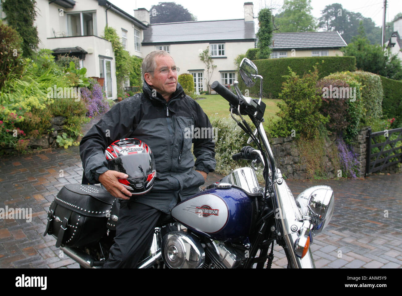 60 Jahre alten Mann mit Harley-Davidson Motorrad außerhalb seines Hauses Leute Lifestyle Wales Stockfoto