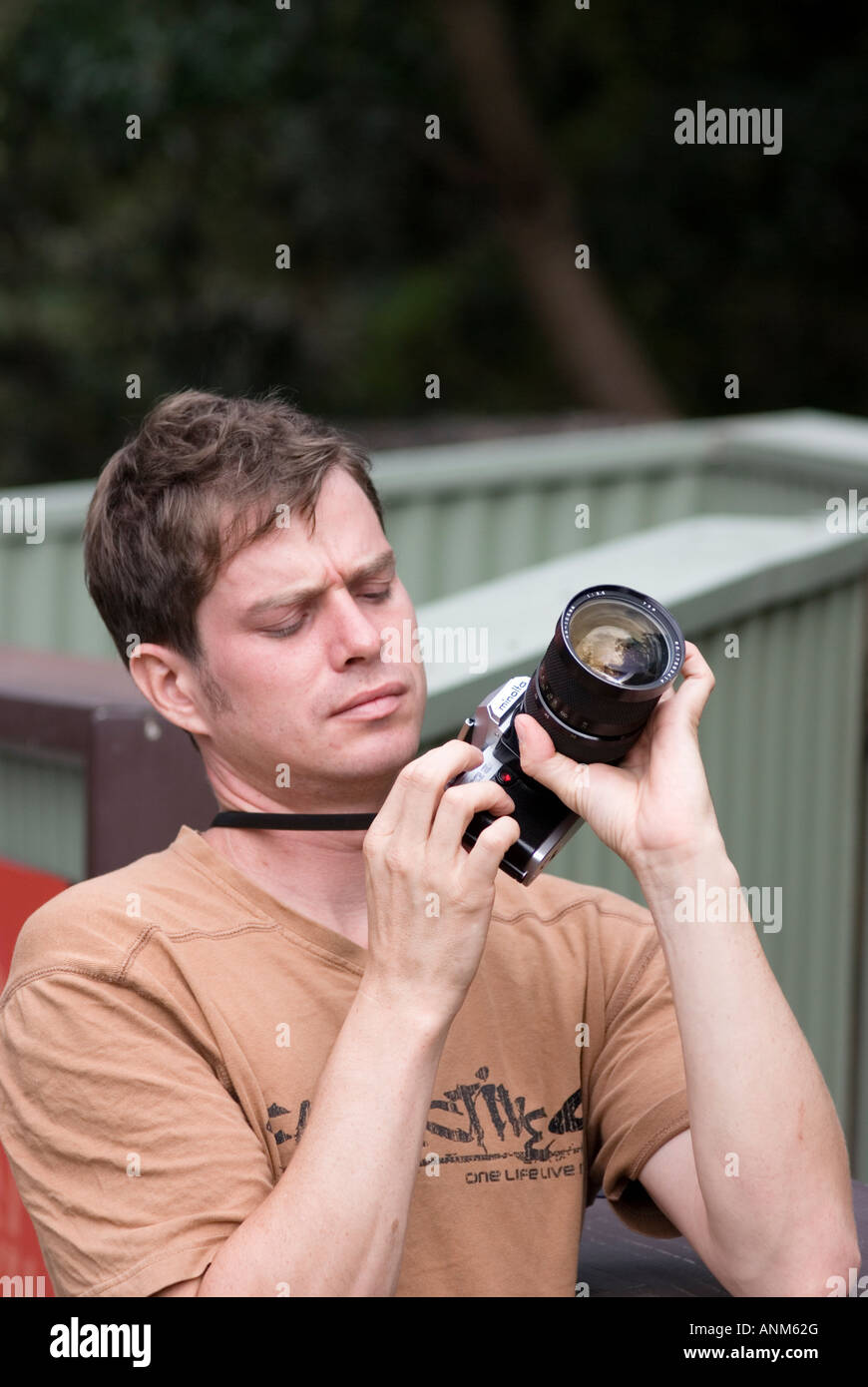 Ein junger Mann ändert die Einstellungen auf seiner Kamera Stockfoto