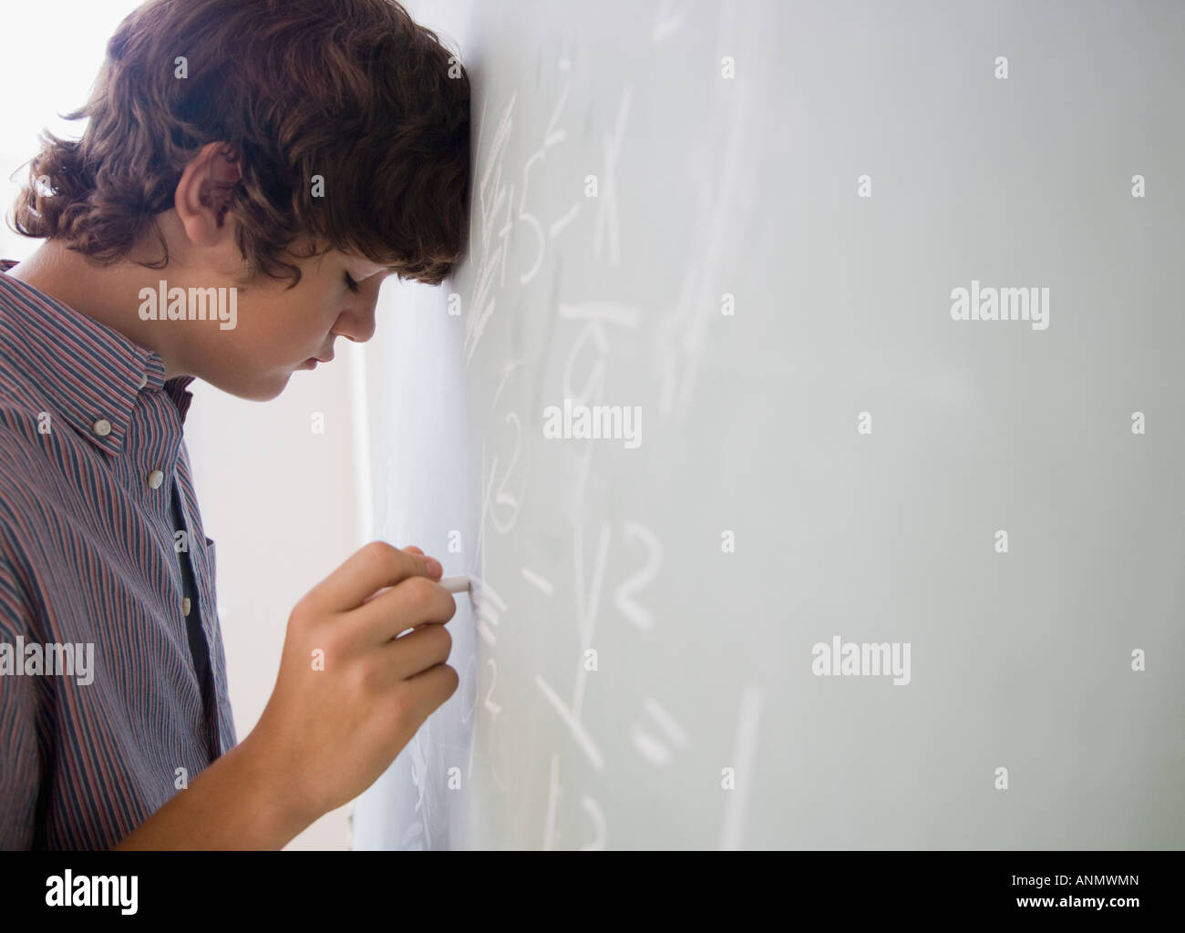 Teenager Boy mathematische Gleichungen auf Tafel schreiben Stockfoto