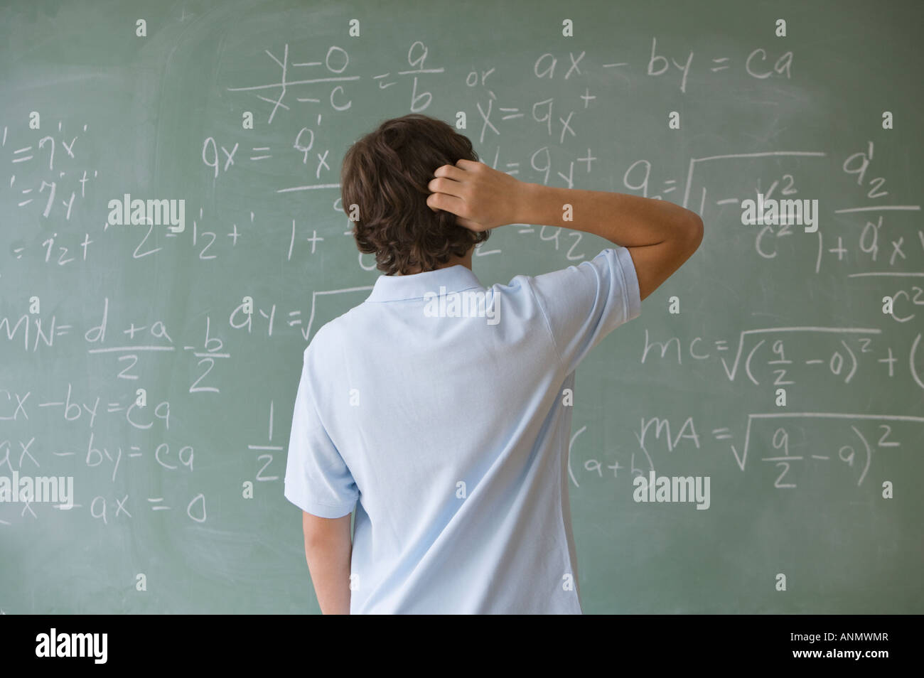 Teenager Boy Blick auf mathematische Gleichungen auf Tafel Stockfoto