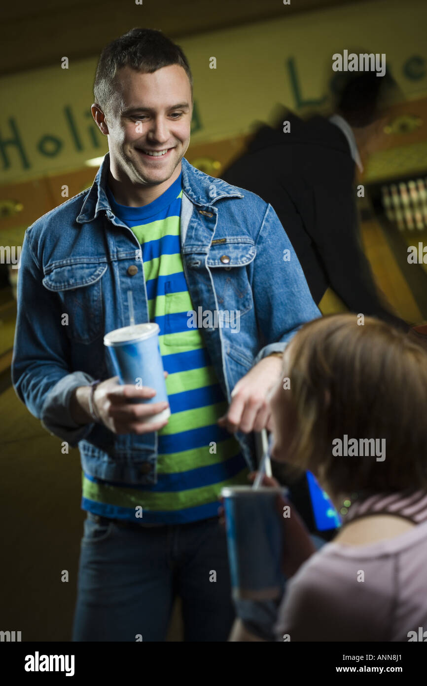 Junger Mann und ein junges Mädchen halten Gläser Cola und sahen einander Stockfoto