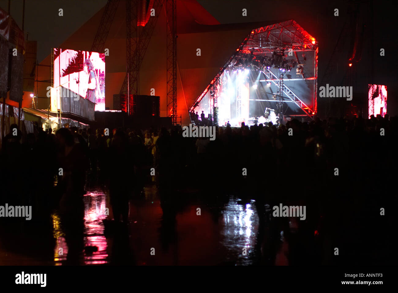 Weiße Streifen Pyramide Bühnenbild mit Menschen in Wasser und Schlamm, die nach starkem Regen in Glastonbury Festival für zeitgenössische darstellende Kunst Somerset England Großbritannien 2005 Rock Band Performance Stockfoto