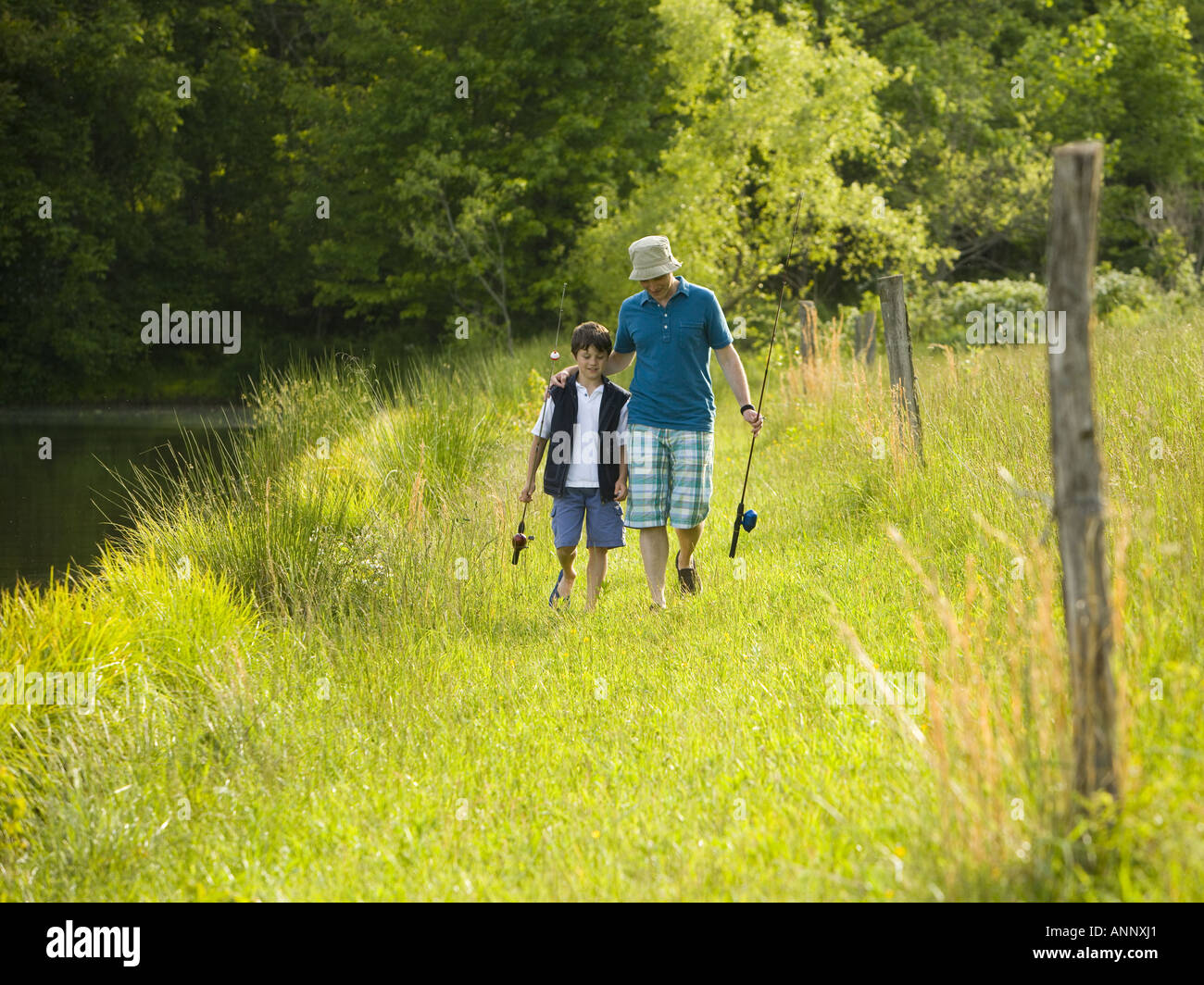 Mann und sein Sohn halten Angelruten und zu Fuß in einem Wald Stockfoto