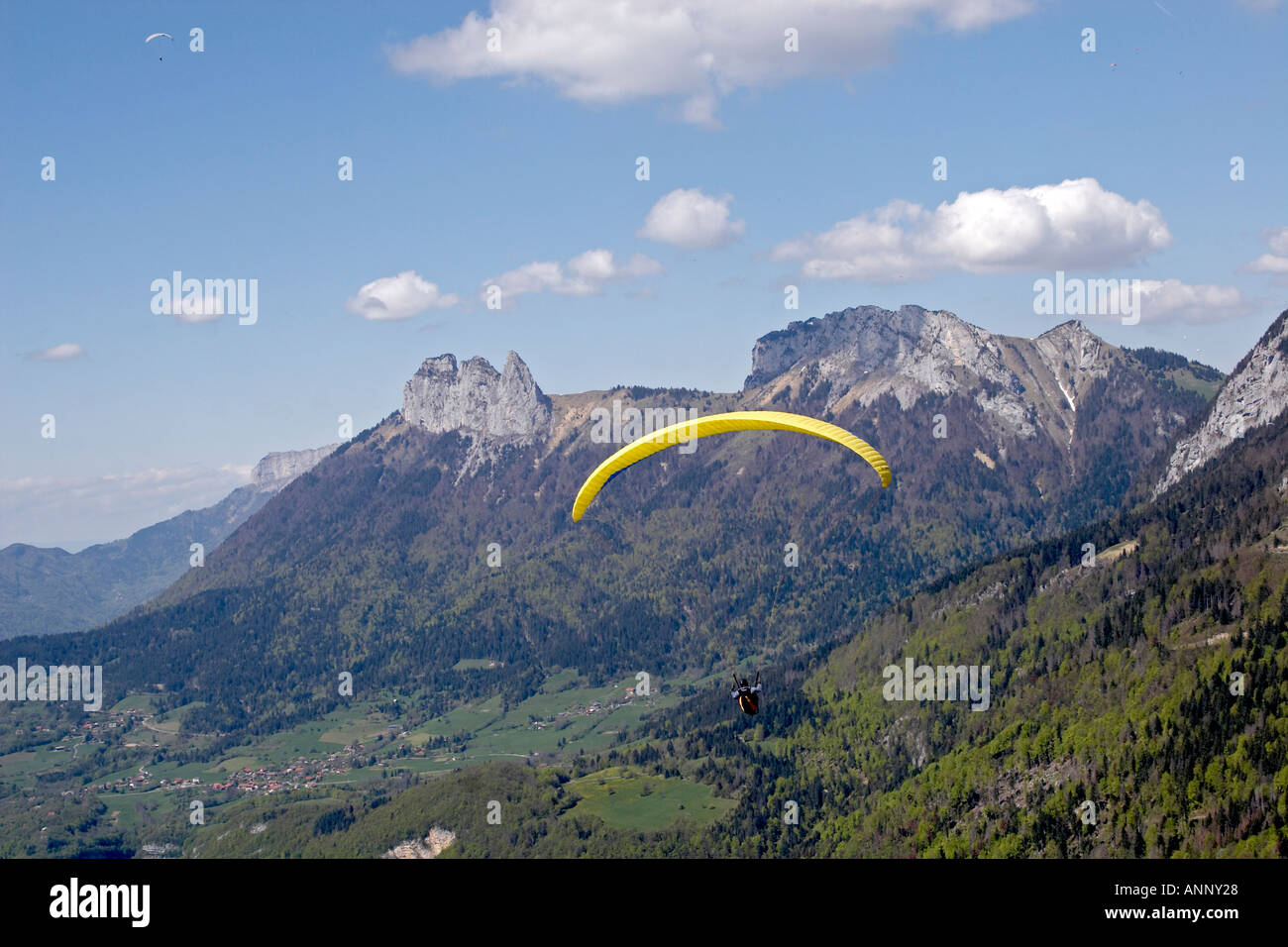 Paragliding Pilot Flying yellow Gleitschirm in den Bergen der Französischen Alpen in der Nähe von Annecy mit Les Dents de Lanfon Haute Savoie Frankreich Stockfoto