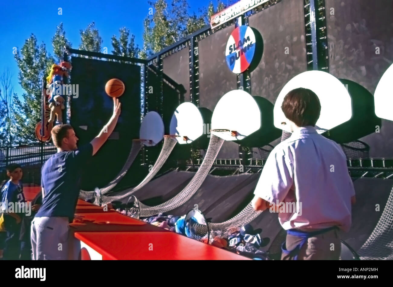 Ein junger Mann schießt gekonnt die Basketball auf einem Vergnügungspark-Spiel namens Slam Dunk gewinnen einen Preis beim Lagune in Utah, USA. Stockfoto