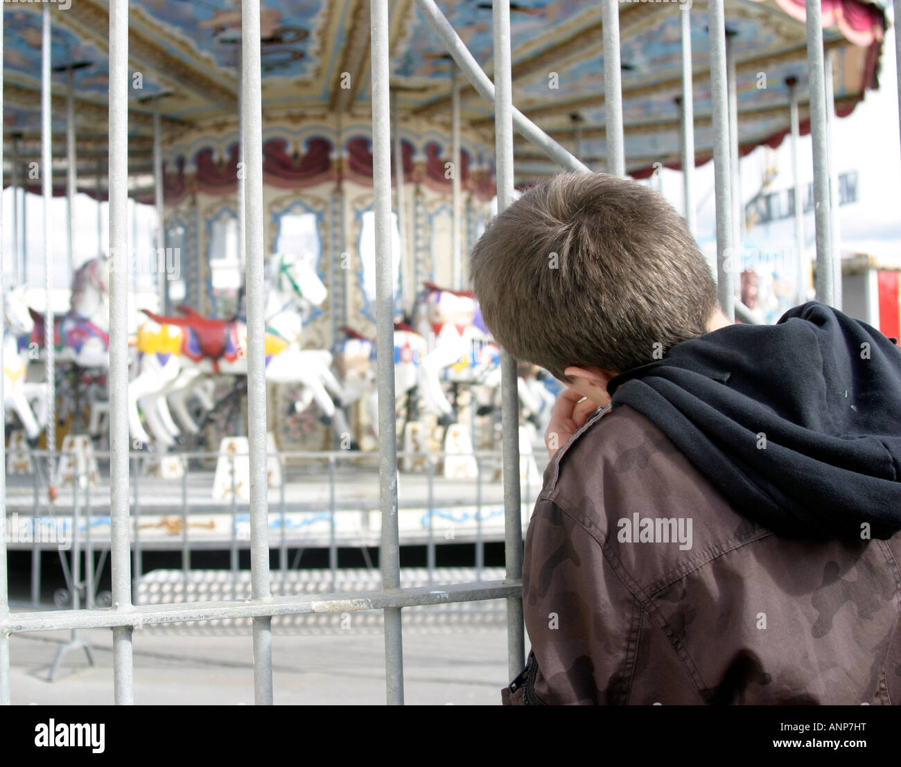Jungen autistische Jugendlichen sieht durch die verschlossenen Tore des Coney Strand Kirmes in Porthcawl, South Wales Stockfoto