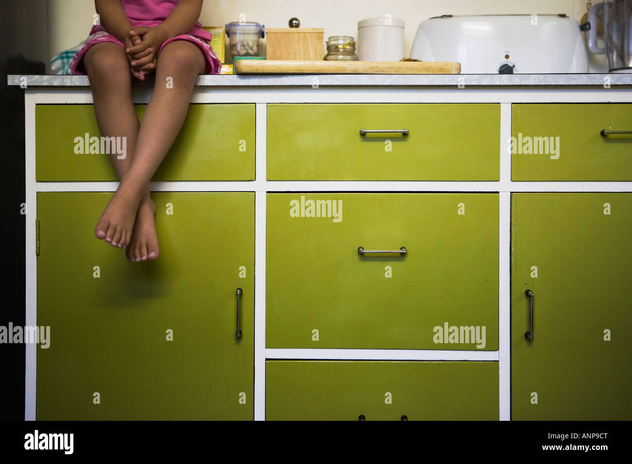Mädchen sitzt auf der Küchenarbeitsplatte Stockfoto