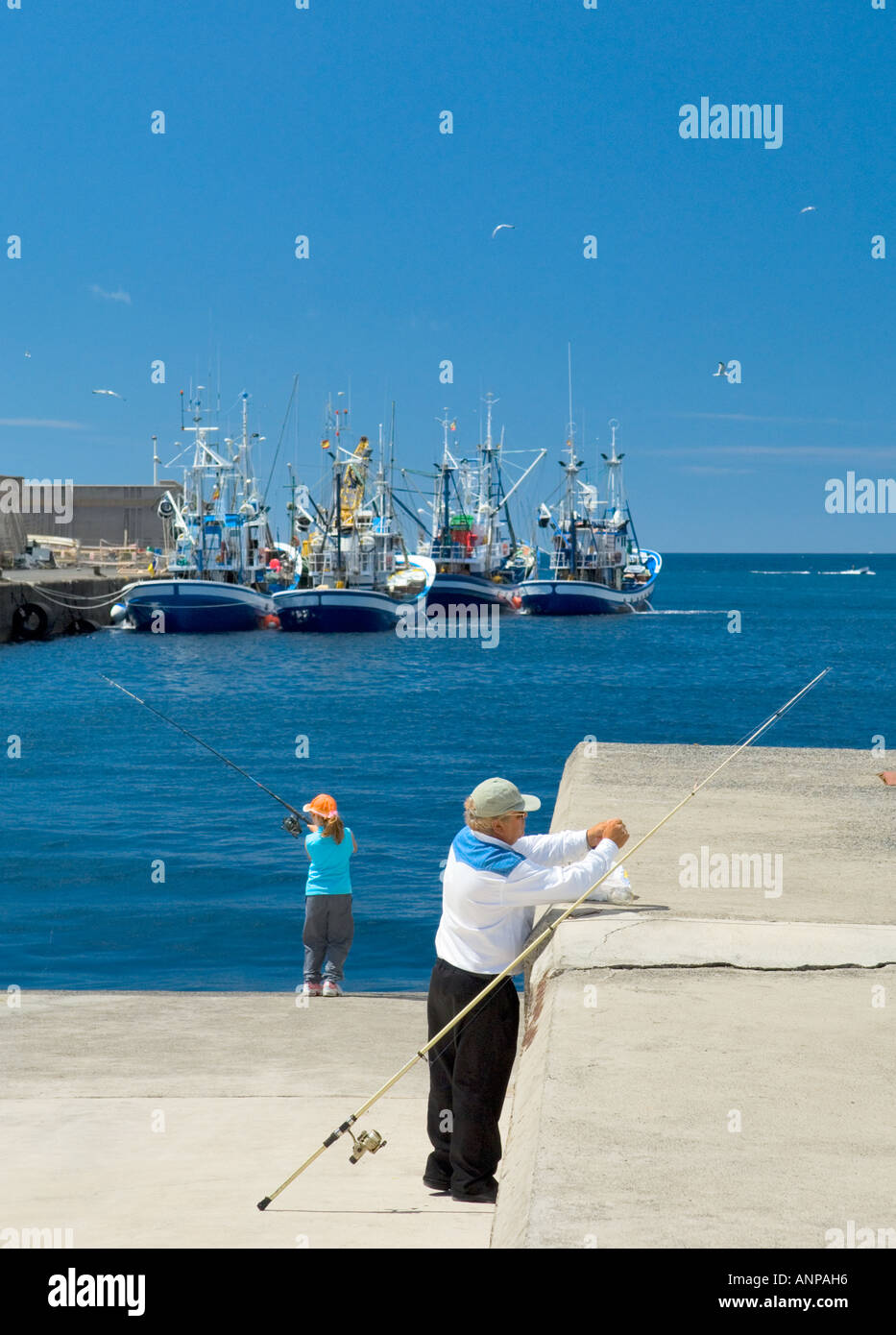 Tiefen La Gsea Flotte Fischerboote und Mann und junge Mädchen Fischen mit Stangen im Hafen von San Sebastian, La Gomera, Kanarische Inseln Stockfoto