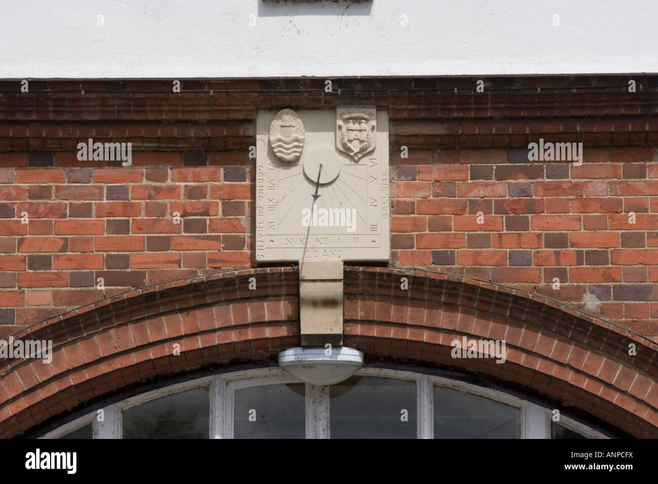 Sonnenuhr als Schlussstein in rotem Backsteinbogen montiert Stockfoto