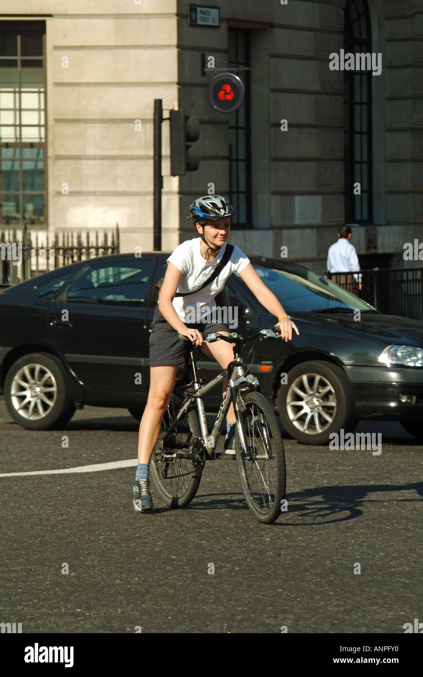 Summer Street Scene Frau Radfahrerin trägt Schutzhelm Reitrad mitten im geschäftigen Verkehr an der Bank Road Junction City of London England UK Stockfoto