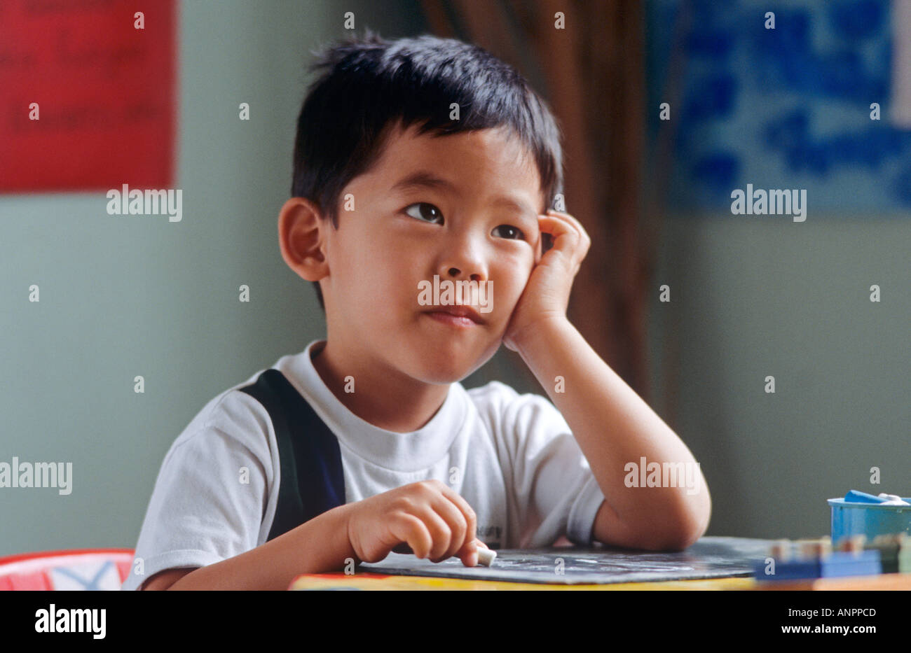 Vier Jahre alten orientalischen jungen im Kindergarten sieht aufmerksam seinem Lehrer Stockfoto