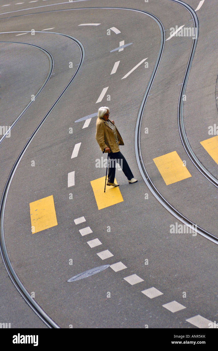 Eine Frau mit einem Gehstock überquert eine leere Straße in Zürich Schweiz Stockfoto