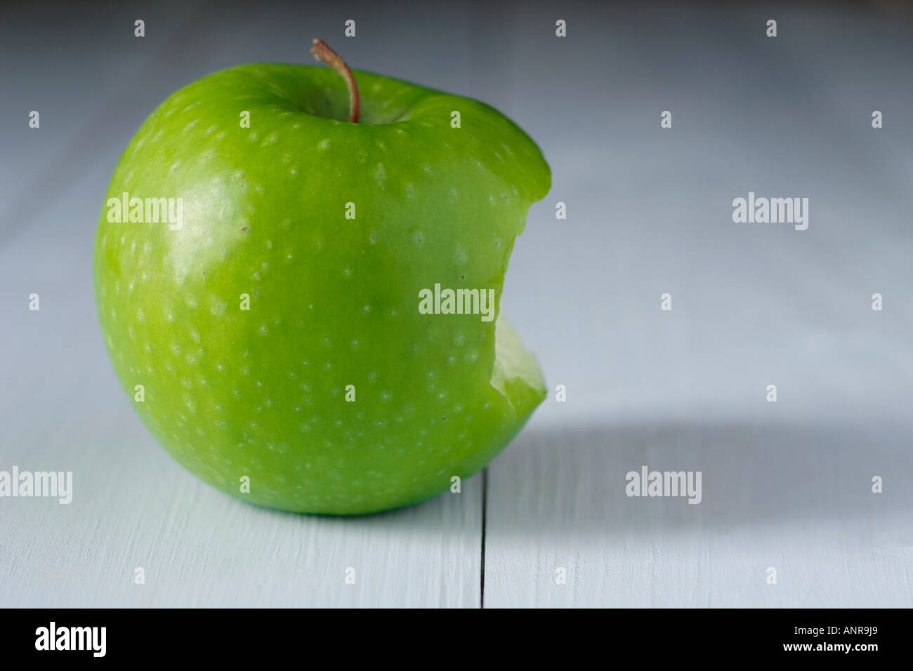 Granny Smith Apfel mit Biss auf blauen Holztisch herausgenommen Stockfoto