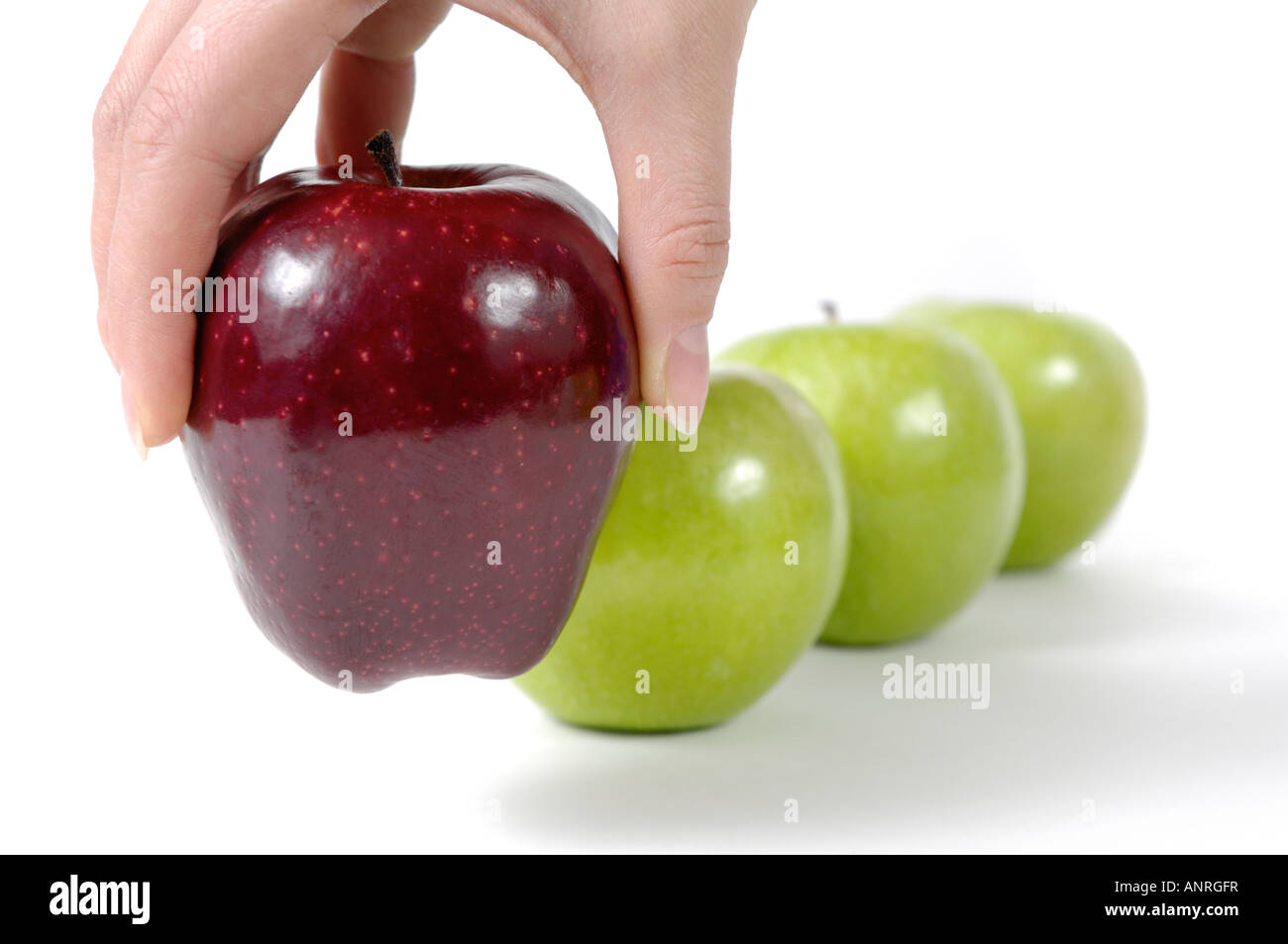 Person, die einen roten Apfel aus einer Reihe von grünen Äpfeln Stockfoto