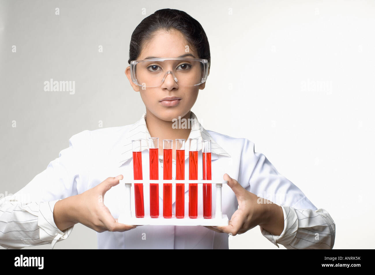 Porträt von einer weiblichen Laborantin hält ein Reagenzglas-Gestell Stockfoto