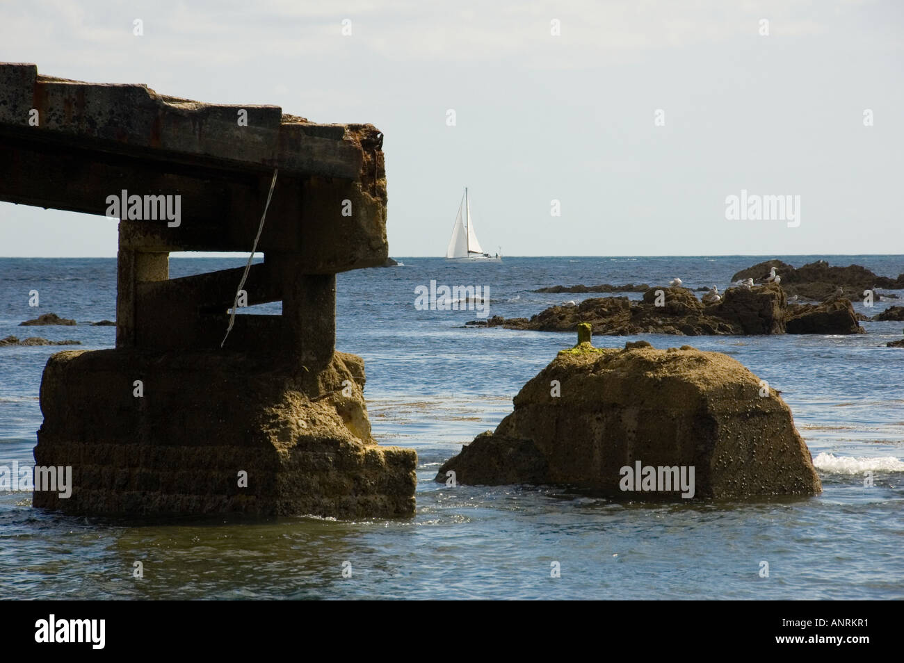 Lizard Point Rettungsboot Slipanlage mit Felsen und einem Segelboot im Hintergrund Stockfoto