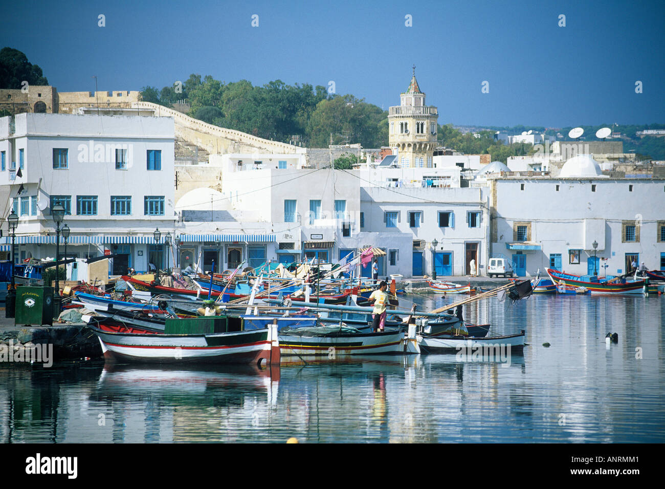 Bunte offene Fischerboote vertäut eng beieinander in den geschützten Gewässern des alten Hafens Corsair in Bizerte, umgeben von blauen und weißen Häuser der medina Stockfoto