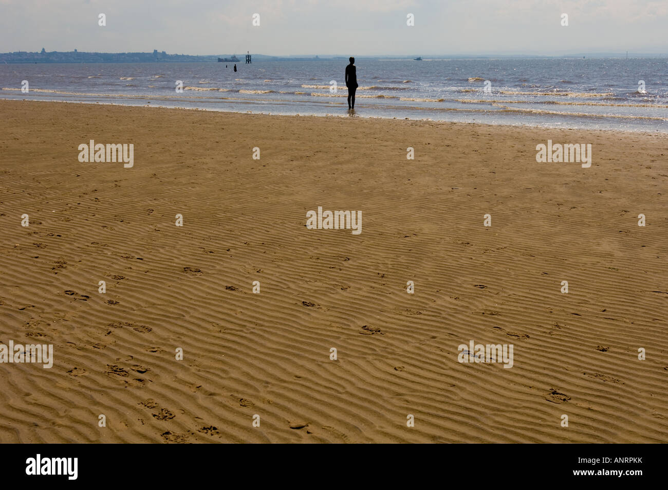 Ein weiterer Ort öffentliche Skulptur: Gewellter Sand eines verlassenen Crosby Strandes mit Antony Gormley Iron Men Skulpturen in der Ferne. UK Stockfoto